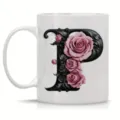 Close-up view of the white ceramic coffee mug featuring an ornate black letter P and pink roses. - Letter P