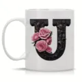 Close-up detail of white ceramic coffee mug featuring ornate black letter U and roses. - Letter U