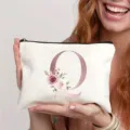 Detailaufnahme einer weißen Canvas-Kosmetiktasche mit Roségold-Buchstabe Q und Rosenmotiv. - Buchstabe Q