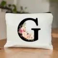 Detailansicht einer weißen Kosmetiktasche mit großem G-Buchstaben und Blumen-Wasserfarbendruck. - Buchstabe G