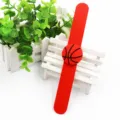 Gros plan du bracelet slap en silicone rouge avec pendentif de basket sur un banc. - Basketball Rouge