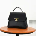 Bolso de mano negro de piel con elegante cierre metálico dorado en T para mujeres. - Negro