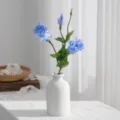 Μπλε τεχνητό μπουκέτο λουλουδιών eustoma σε λευκό κεραμικό βάζο για διακόσμηση σπιτιού. - Μπλε