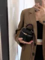 Primer plano detallado del mini bolso acolchado negro sostenido con elegancia. - S / Negro