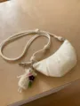 Borsa a tracolla croissant minimalista in pelle bianca con cinturino annodato e portachiavi. - Bianco