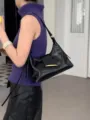 Detailweergave van minimalistische zwarte lakleren schoudertas, stijlvol hobo-ontwerp. - Zwart