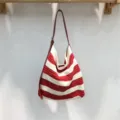 Vista dettagliata di una borsa a tracolla in maglia a righe rosse e bianche appesa. - Rosso