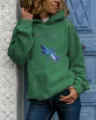 Detail view of the green hoodie featuring a blue dragonfly and inspirational text print. - Green