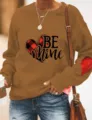 Close-up detail of the brown sweatshirt featuring heart graphic and lovely print. - Khaki