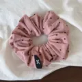 Close-up of pink polka dot hair scrunchie with cute bow tag, soft fabric for daily hair styling. - Pink