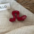 Gros plan détaillé de la pince à cheveux en acétate rouge, texture brillante et design unique. - Rouge