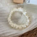 Detail view of the elegant cream silk hair scrunchie, soft satin material for daily hair styling. - Off White