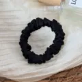 Detail view of a black silk hair scrunchie, satin material, elegant and gentle on hair. - Black