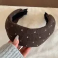Gros-plan sur le serre-tête large en laine marron avec motif cœur pailleté, accessoire hiver. - Marron