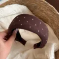 Gros plan détaillé d'un serre-tête en tricot marron à pois, accessoire en tissu doux. - Serre-Tête Large Café