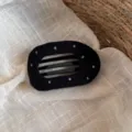 Vue détaillée d'une pince à cheveux en tissu noir à pois blancs pour des coiffures élégantes. - Pince à Cheveux Pois Noire