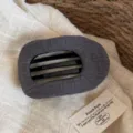 Pince à cheveux en tissu gris foncé avec rayures texturées, gros plan montrant le design. - Pince à Cheveux Rayée Gaufrée / Gris