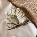 Gedetailleerd overzicht van beige haarscrunchie met stippen en een bruine leren strik. - Leren Koord Strik Scrunchie / Beige Zwarte Punten