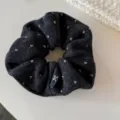 Gros plan détaillé du chouchou en laine noire avec jolis motifs de cœurs et étiquette nœud. - Chouchou / Chouchou noir