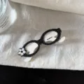 Close-up detail of the black and white checkered glasses shaped hair clip with cute flower. - Black Frame Glasses Clip with Small Flower