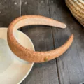 Gros plan sur le serre-tête en paille tressée marron avec un délicat détail en métal doré. - Serre-tête / Marron