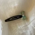 Vista detallada de un lindo pasador de pelo de acetato con lazo y base negra para uso diario. - Verde