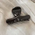Primo piano dettagliato di un morsetto per capelli marrone scuro lucido su sfondo in tessuto. - Marrone scuro