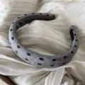 Primo piano di un elegante cerchietto grigio con dettagli classici a pois neri in tessuto. - Cerchietto a Tesa Larga a Pois / Grigio
