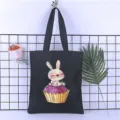 Detail view of black canvas tote bag featuring cute watercolor rabbit and cupcake print scene. - Style 13 / 35*40cm