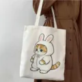 Vista detallada del bolso tote de lona blanca con lindo diseño de gato para uso diario. - Estilo de Gato Naranja con Capucha de Conejo