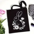 Minimalist black canvas tote bag featuring cute white rabbit and floral print, perfect for daily use. - Black Rabbit Flower Bush Print Style / L