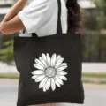 Gros plan sur le sac cabas en toile noire avec un imprimé marguerite blanche pour un usage quotidien. - Style Marguerites Délicates / 35*40cm