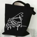 Minimalist black canvas tote bag with white line art piano player graphic for daily commute. - Black Piano Player Abstract Line Drawing Style / L