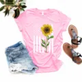 Detalle de camiseta rosa de manga corta con grafico de girasol y bandera en plano. - Rosa