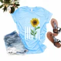 Vista detallada de camiseta azul claro de manga corta con estampado de girasol y bandera de EE. UU. - Azul claro