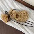 Detailed close-up view of a chic leopard print mesh hair bow clip adorned with brown ribbons. - Bow Banana Clip / Yellow Leopard