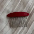 Detail view of red acetate hair comb with metal tines, featuring fine craftsmanship and polished finish. - Gold Label Oval Comb - Red