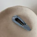 Close-up of blue floral fabric BB hair clip detail placed in minimalist ceramic dish. - Blue Hollow