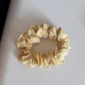 Vista dettagliata di un elastico per capelli in tessuto a righe gialle con trama plissettata. - Elastico Arricciato Giallo-Righe Sottili