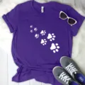 Close-up detail of purple short-sleeve t-shirt with white animal paw prints design layout. - Purple (White Paw Print)