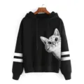 Nahaufnahme des schwarzen Hoodies mit weißen Doppelstreifen und niedlichem Katzenmotiv. - Schwarz