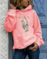 Detailed view of women's coral pink long sleeve hoodie with colorful abstract cat print. - Pink