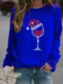 Close-up detail of women's blue Christmas wine glass print sweatshirt worn with jeans. - Blue
