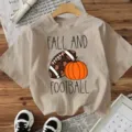 Casual beige short sleeve t-shirt featuring fall football pumpkin graphic for daily wear. - Apricot
