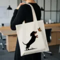 Vue détaillée d'un sac cabas en toile beige avec motif teckel et papillon pour un usage quotidien. - Imprimé Teckel / 35x40cm