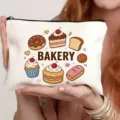 Detailopname van wit canvas cosmetisch tasje met schattige cartoon bakkerij print en ritssluiting. - Bakken Cartoon
