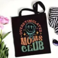 Black canvas tote bag detail featuring retro graphic print and lifestyle scene props. - Style 6