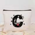 Gros plan détaillé de la trousse de maquillage en toile blanche avec imprimé lettre C. - Style Lettre C