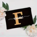 Black canvas cosmetic pouch with gold letter F and white custom name print, floral detail. - Letter F