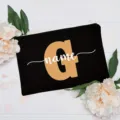 Detailed shot of a black canvas cosmetic bag featuring a custom initial G and floral decor. - Letter G